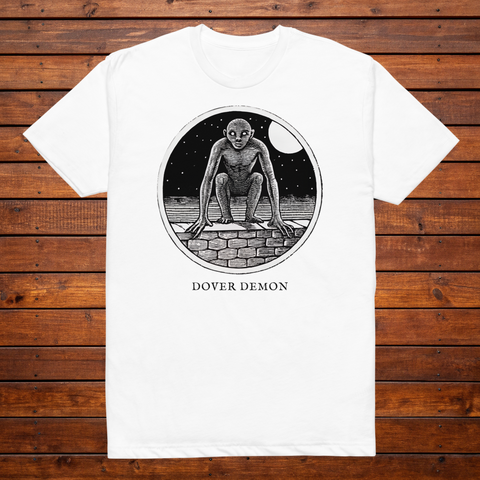 Dover Demon engraved cryptid t-shirt — black and white crosshatch medallion design on white tee, flat lay