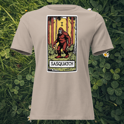 Bigfoot tarot card design on Heather Stone t-shirt flat lay on grass — Lost Arcana series by Cryptid Emporium
