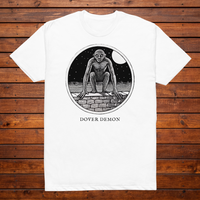 Dover Demon engraved cryptid t-shirt — black and white crosshatch medallion design on white tee, flat lay