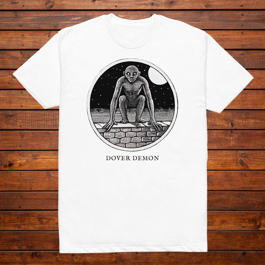 Dover Demon engraved cryptid t-shirt — black and white crosshatch medallion design on white tee, flat lay