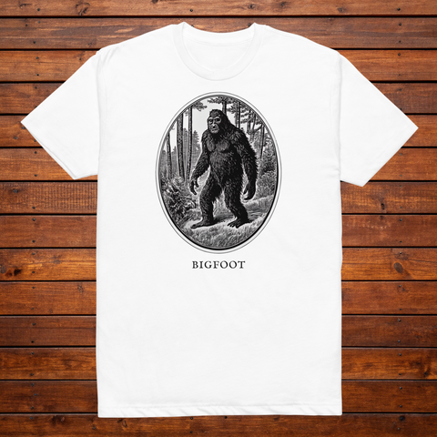 Bigfoot engraved cryptid t-shirt — black and white crosshatch medallion design on white tee, flat lay