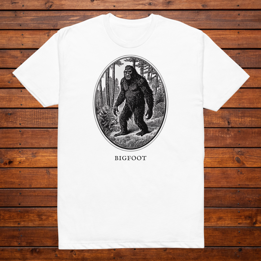 Bigfoot engraved cryptid t-shirt — black and white crosshatch medallion design on white tee, flat lay